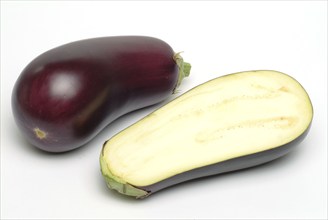 Aubergine, Solanum melongena, egg plant, single ripe fruit and halved fruit next to it