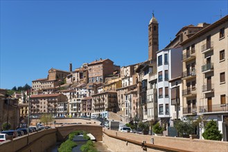 Historic town with many buildings and a prominent tower in the background next to a river under a