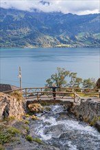 Person enjoying the view of the lake and mountains from a bridge, St. Beatus Caves, Switzerland,