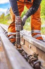 A construction worker uses a tool to fix the railway rails on the track, rail welding, track