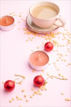 Christmas or New Year composition. Decorations, red balls, cup of coffee, on a pink paper