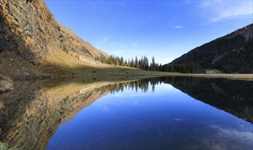 An expansive panorama shows a lake with clear mountain reflections, Felbertal, Mittersill,