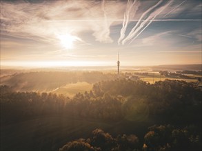 Landscape with a transmission tower at sunrise, seen from above, with clouds in the sky and golden