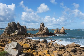 Rocky coastal landscape with crashing waves and a clear blue sky with light clouds, Plage de Pors