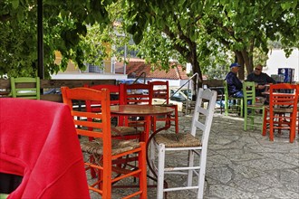 Terrace under trees, colourful chairs and tables in front of a café, small town Leonidio, Tsakonia,