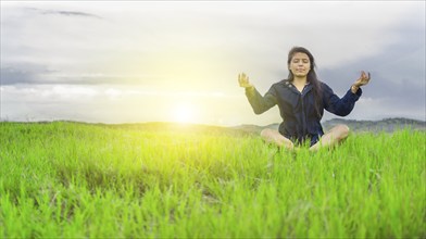 Relaxed woman doing yoga in the field, concentrated and meditati