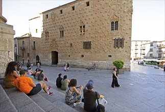 Castilian street musician and spectator at Casa de las Conchas, Salamanca, province of Salamanca,