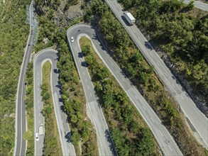 Mountain pass road with multiple hairpins, water pipeline, aerial view, drone shot. Valais,