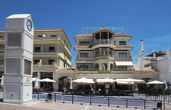 Clock tower and Mediterranean buildings with balconies and cafés in sunny weather, Plaza de España,