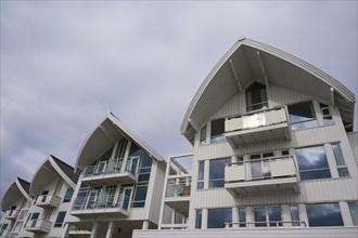 A modern residential building with several balconies and glass fronts under a cloudy sky, Molde,