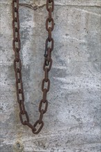 Close-up of heavy security chain with rusted links against a cement block background, Quebec,