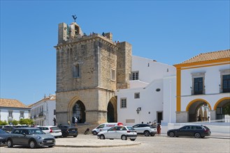 Historic church with bell tower, surrounded by cars and white buildings, in sunny weather, Sé