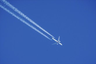 Emirates aircraft in the sky, contrails