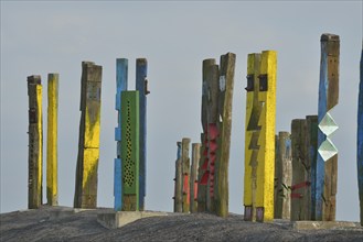 A creative art installation of colourfully painted wooden posts with abstract patterns against a