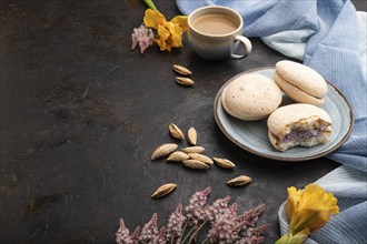 Meringues cakes with cup of coffee on a black concrete background and blue linen textile. Side