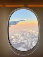 View from aeroplane window, porthole, Emirates airline, Airbus A380-800, sunset over the clouds,