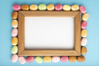 Composition with candies and wooden frame on blue pastel background. copy space, top view, flat