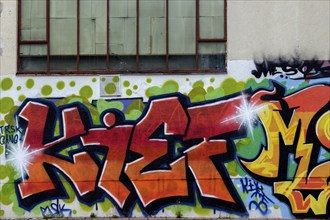 Colourful graffiti artwork with red letters on an urban wall with window, Rhineland-Palatinate,