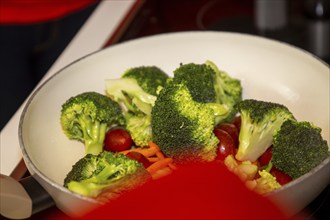 Vegan cooking: Close-up of a pan with broccoli, carrots and cocktail tomatoes