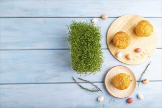 Homemade cakes with chocolate eggs and carrot microgreen on a blue wooden background. top view,