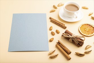 Composition with gray paper sheet, almonds, cinnamon and cup of coffee. mockup on orange background