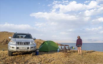 Hiker in front of a tent, camping in the highlands, Song Kul mountain lake, Naryn region,