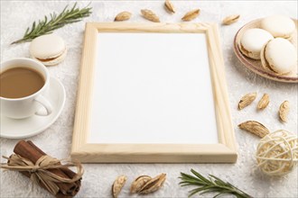 White wooden frame mockup with cup of coffee, almonds and macaroons on gray concrete background.