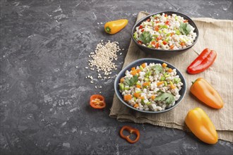 Pearl barley porridge with vegetables in blue ceramic bowls on a black concrete background and