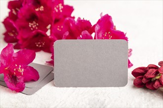 Gray business card with purple azalea flowers on gray concrete background. side view, copy space,