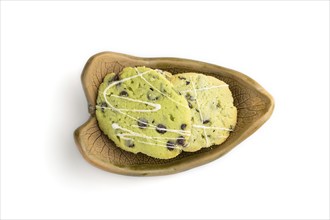 Green cookies with chocolate and mint on leaflike ceramic plate isolated on white background. top