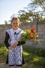 Schoolgirl with a bouquet of flowers on her first day at school, Issyk-Kul region, Kyrgyzstan, Asia