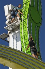 Two employees working high up on the Chaos Pendulum ride, Cranger Kirmes, Herne, Ruhr area, North