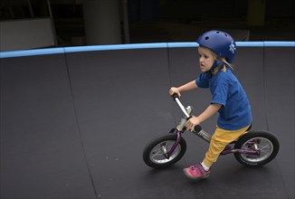 Little girl, 3 years, blonde, helmet, helmet, riding on balance bike, bicycle, skating rink,