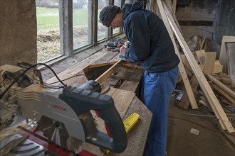 Young man planing on the workbench in his workshop, Mecklenburg-Vorpiommern, Germany, Europe