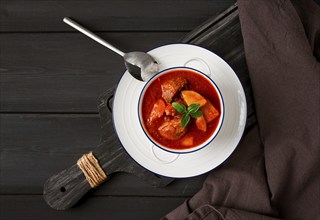 Stew with potatoes, in tomato sauce, with spices and herbs, close-up, no people, on a black