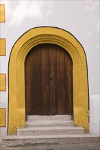 Old wooden entrance door with doorstep and yellow contour on facade of Stadtsall hotel building in