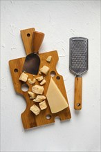 Hard cheese, parmesan, on a cutting board, cheese knife, grater, top view, no people