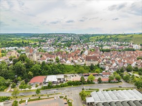 Overview of a town with red tiled roofs, embedded in hilly, green landscapes, crossed by various