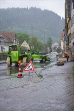 A construction site in a town in the rain, construction workers and excavators working on a wet