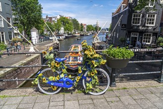 Sint Antoniesluis, on the Oudeschans canal, bicycle decorated with sunflowers, canal cruise boat,