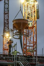 Concrete work, at dusk, on a large construction site building a residential and commercial complex,