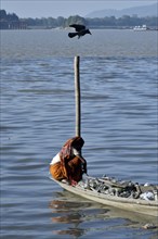 Rag picker collecting plastic bottle and other plastic materials in a boat from the bank of