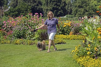 Woman takes Lhasa Apso for a walk in the park