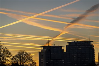 Condensation trails from aircraft flying at high altitude, evening sky, after sunset