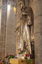 Metal statue in a church, surrounded by flowers, shown in architectural detail, Paris