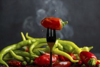 A red pepperoni on a fork, pepperoni and some smoke in the background, food photography