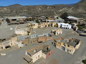 Close-up of an abandoned Wild West town with various buildings in the desert, aerial view, Fort