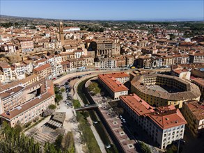 Aerial view of a historic city with tiled roofs, bridges over a river and a central square, aerial