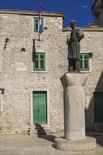 Statue of historic figure Giorgio da Sebenico / Juraj Dalmatinac in front of an old stone building,