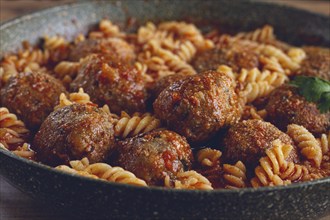 Minced meat meatballs, in tomato sauce, with fusilli pasta, in a cast-iron pan, homemade, no people